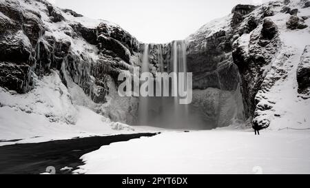 Ein Mann steht vor dem berühmten gefrorenen isländischen Wasserfall Stockfoto