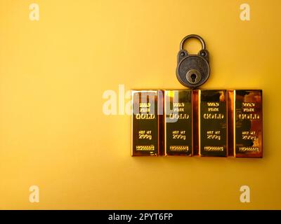 Vintage-Vorhängeschloss mit goldenem Balken auf gelbem Hintergrund. Stockfoto