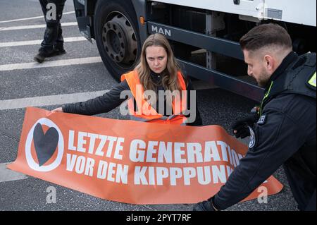 28.04.2023, Berlin, Deutschland, Europa - Eine Klimaprotestierende der so genannten Letzte Generation hat sich auf den Asphalt einer Straße geklebt. Stockfoto