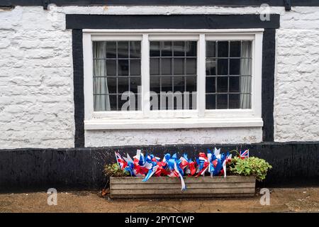 Bray, Berkshire, Großbritannien. 5. Mai 2023. Die Bewohner von Bray Village in Berkshire waren damit beschäftigt, Union Jack mit roten, weißen blauen Schleifen vor ihren Hütten in der Bray High Street vor der Krönung morgen zusammenzubringen. Kredit: Maureen McLean/Alamy Live News Stockfoto