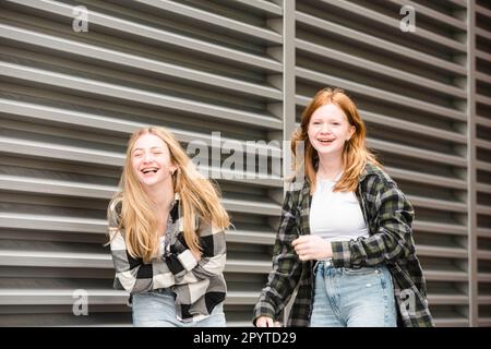 Zwei lachende Teenager, die zusammen gehen. Stockfoto