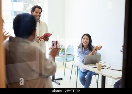 Männlicher Unternehmer zeigt glücklichen Kollegen im Café ein Smartphone Stockfoto