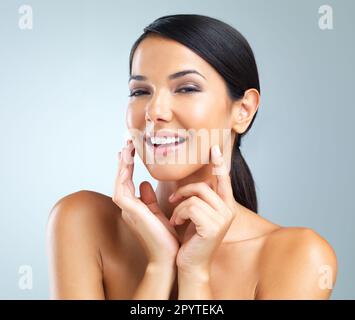 Make-up, wer es braucht. Studio-Porträt einer schönen jungen Frau, die ihre Haut berührt. Stockfoto