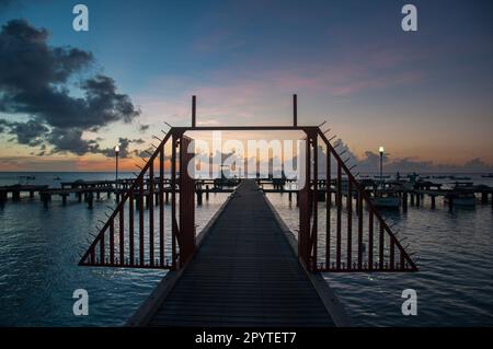 Legen Sie mit Booten und Segelbooten an einem Strand in Aruba an, bei Sonnenuntergang, Ne Stockfoto