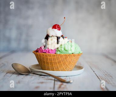 Eisbecher in einer Waffelschüssel auf einem verwitterten Holztisch. Stockfoto