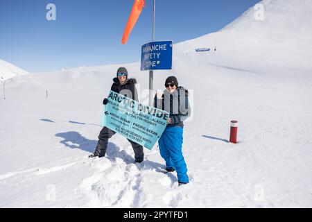 Zwei Frauen mit einem Arctic Divide Schild in Alaksa am Dalton Highway Stockfoto