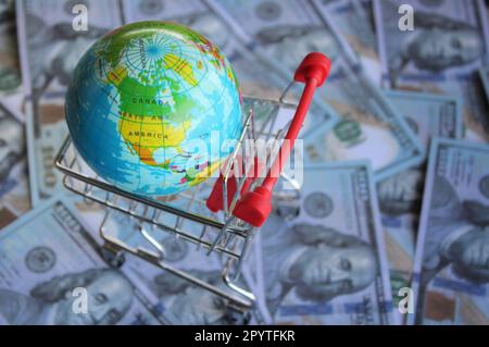 Erdkugel in einem Einkaufswagen auf der Höhe des Geldes. Globaler Markt, internationales Geschäftskonzept Stockfoto