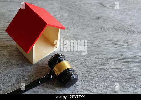 Spielzeughaus und Hammer auf einem Holztisch mit Platz zum Kopieren. Immobilienrecht und Hausauktionskonzept Stockfoto