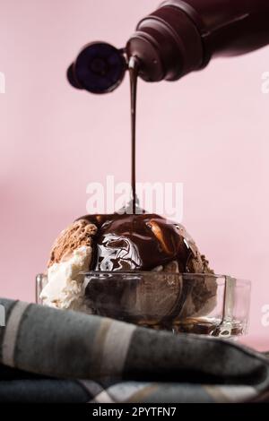 Ich gieße Schokoladensoße auf Eis in eine Tasse Stockfoto