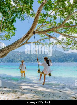 Ein Paar spielt an einer Seilschaukel am Strand von Ko Ra WI Island Süd-Thailand, ein tropischer weißer Sandstrand mit türkisfarbenem Ozean im Tarutao National Park, Koh Rawi, Tambon Ko Tarutao Stockfoto