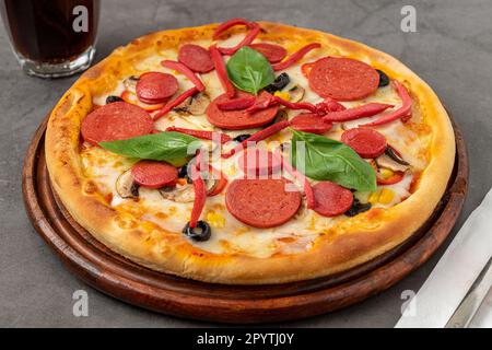 Gemischte Pizza mit Wurst, Salami und Pilzen auf einem Steintisch Stockfoto