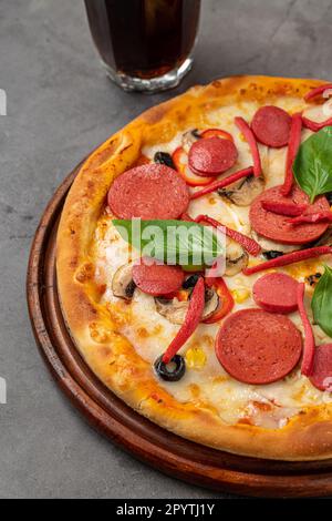 Gemischte Pizza mit Wurst, Salami und Pilzen auf einem Steintisch Stockfoto