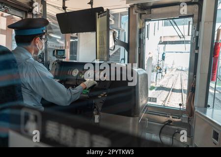 Asiatischer Zugführer am Arbeitsplatz, Blick von hinten Stockfoto