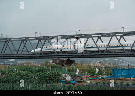 SHIZUOKA, JAPAN - 6. APRIL 2023: Tokaido Shinkansen überquert die Fuji View Shinkansen Eisenbahnbrücke am Abend Stockfoto