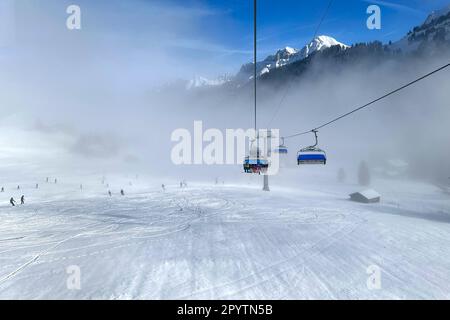 AUS DER SERIE ADELBODEN Seilbahn im Schnee vor der winterlichen Landschaft in Adelboden, Berner Oberland, Kanton Bern, Schweiz. Die malerische Stadt Adelboden ist eine Schweizer Idylle in den Berner Alpen, beeindruckende Gipfel, einzigartige Winterlandschaft, beliebtes Skigebiet, Alpenweiden, Rauschende Wasserfälle, gemütliche Holzhäuser. Aufgrund des Klimawandels und immer weniger Schnee, orientiert sich das klassische Wintersportresort neu, und die Sommersaison gewinnt an Bedeutung Stockfoto