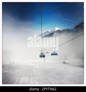 AUS DER SERIE ADELBODEN Seilbahn im Schnee vor der winterlichen Landschaft in Adelboden, Berner Oberland, Kanton Bern, Schweiz. Die malerische Stadt Adelboden ist eine Schweizer Idylle in den Berner Alpen, beeindruckende Gipfel, einzigartige Winterlandschaft, beliebtes Skigebiet, Alpenweiden, Rauschende Wasserfälle, gemütliche Holzhäuser. Aufgrund des Klimawandels und immer weniger Schnee, richtet sich das klassische Wintersportresort neu aus, und die Sommersaison wird immer wichtiger Foto mit iPhone, Hipstamatic App. Stockfoto