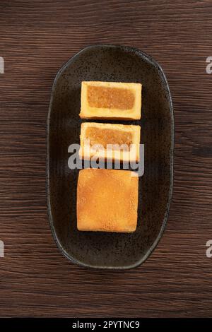 Köstliches taiwanesisches berühmtes Ananaskuchen Gebäck als Dessert auf einem Teller auf einem Holztisch mit heißem Tee. Stockfoto