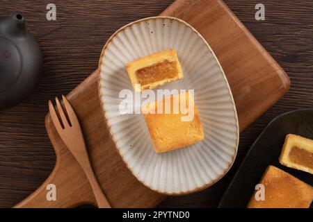 Köstliches taiwanesisches berühmtes Ananaskuchen Gebäck als Dessert auf einem Teller auf einem Holztisch mit heißem Tee. Stockfoto