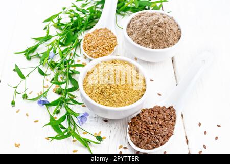 Leinenkleie und Mehl in zwei Schüsseln, Samen in Löffeln, Leinenblätter und Blumen auf dem Hintergrund eines hellen Holzbretts Stockfoto