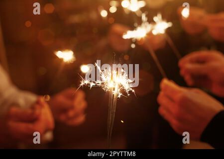 Eine Gruppe von Freunden, die Weihnachten feiern, Hände mit glitzernden Lichtern Stockfoto