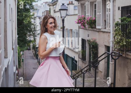 Fotoshooting in Paris in Montmartre, Porträt einer jungen, lächelnden Frau, die vor die Kamera schaut Stockfoto