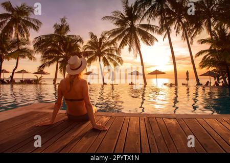 Strandurlaub im Luxushotel, tropischer Urlaub im Luxusresort, Frau sitzt am Pool Stockfoto