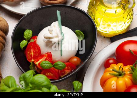 Burrata-Käse, verschiedene Tomaten und Oliven. Italienische Küche Stockfoto