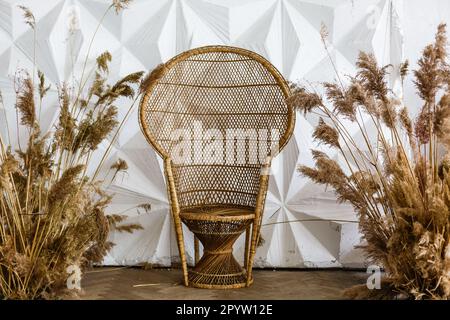 Korbsessel Peacock in einem geräumigen Schlafzimmer. Rattan-Pfau-Sessel an der weißen, leeren Wand im Wohnzimmer. Haus im skandinavischen Stil Stockfoto