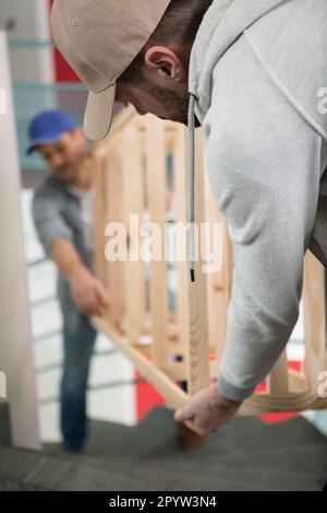 Zwei junge Männer in Uniform, die Möbel auf der Treppe tragen Stockfoto