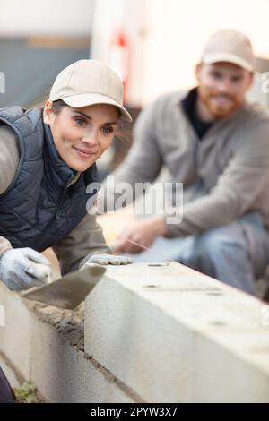 Weiblicher Maurer, der eine neue Wand legt Stockfoto