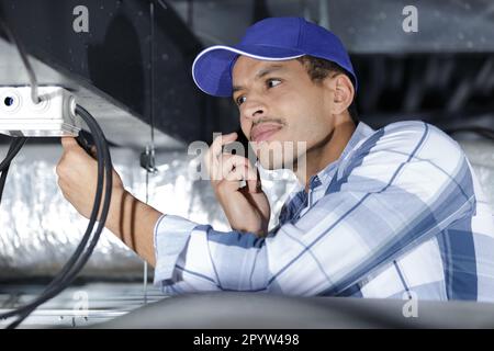 Elektriker am Telefon mit Kabeln Stockfoto