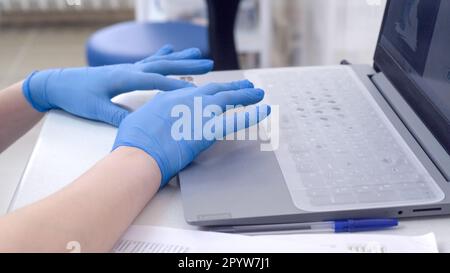 Arzt oder Krankenschwester Hände in blauen Nitril medizinischen Handschuhen Tippen auf Laptop Computer Tastatur im Krankenhaus Stockfoto