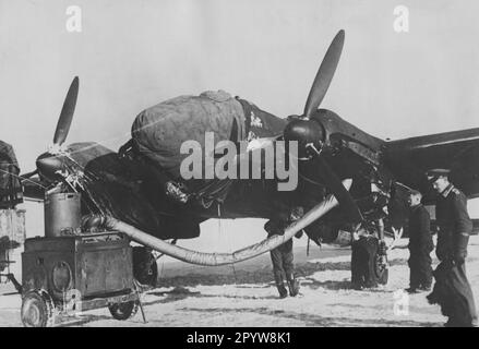 Auf einem Flugplatz wird der Motor eines Heinkel He 111 mit einem mobilen Heizelement beheizt. Planen bedecken den anderen Triebwerkrumpf und das Cockpit des Flugzeugs. Foto: Bankhardt [automatisierte Übersetzung] Stockfoto