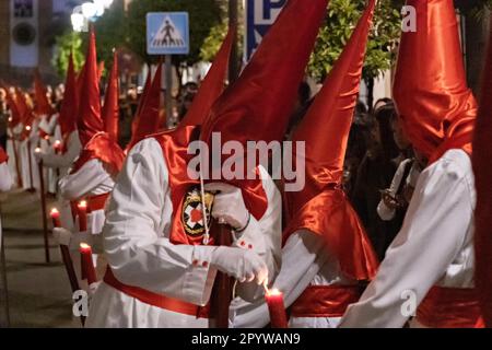 Cofradias, die rote konische Kapuzen tragen, zünden ihre Kerzen während der Mitternachtsstummen Prozession an, die Karfreitag in der Heiligen Woche oder Semana Santa, 6. April 2023 in Ronda, Spanien, feiert. Ronda, die sich im 6. Jahrhundert v. Chr. niedergelassen hat, hält seit über 500 Jahren Heilige Woche-Prozessionen ab. Stockfoto