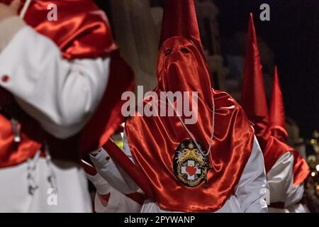 Cofradias mit roten konischen Kapuzen laufen während der Mitternachtsstummprozession am Karfreitag in der Heiligen Woche oder Semana Santa, 6. April 2023 in Ronda, Spanien, durch die Straßen. Ronda, die sich im 6. Jahrhundert v. Chr. niedergelassen hat, hält seit über 500 Jahren Heilige Woche-Prozessionen ab. Stockfoto