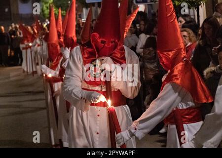 Cofradias, die rote konische Kapuzen tragen, zünden ihre Kerzen während der Mitternachtsstummen Prozession an, die Karfreitag in der Heiligen Woche oder Semana Santa, 6. April 2023 in Ronda, Spanien, feiert. Ronda, die sich im 6. Jahrhundert v. Chr. niedergelassen hat, hält seit über 500 Jahren Heilige Woche-Prozessionen ab. Stockfoto