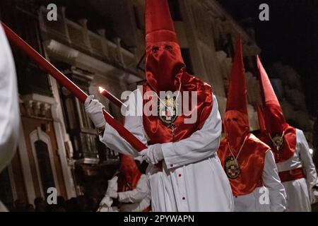 Cofradias mit roten konischen Kapuzen laufen während der Mitternachtsstummprozession am Karfreitag in der Heiligen Woche oder Semana Santa, 6. April 2023 in Ronda, Spanien, durch die Straßen. Ronda, die sich im 6. Jahrhundert v. Chr. niedergelassen hat, hält seit über 500 Jahren Heilige Woche-Prozessionen ab. Stockfoto