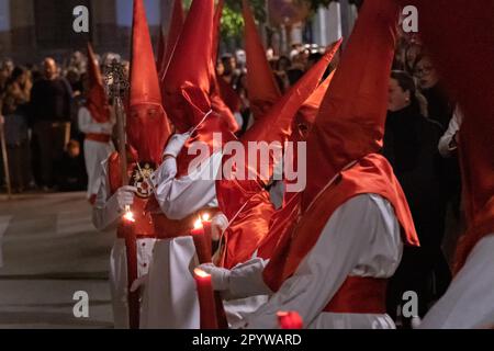 Cofradias mit roten konischen Kapuzen laufen während der Mitternachtsstummprozession am Karfreitag in der Heiligen Woche oder Semana Santa, 6. April 2023 in Ronda, Spanien, durch die Straßen. Ronda, die sich im 6. Jahrhundert v. Chr. niedergelassen hat, hält seit über 500 Jahren Heilige Woche-Prozessionen ab. Stockfoto