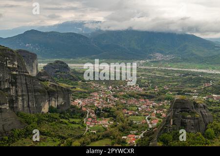Ein Blick aus der Vogelperspektive auf eine malerische Bergstadt, eingebettet in die sanften Hügel. Meteora, Kalabaka, Griechenland. Stockfoto