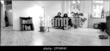 Berlin-Neukölln. Wohn- und Innenbereich: Wohnzimmer mit Parkettboden und weißen Wänden. Ein junges Paar sitzt auf einem Sofa, alle Möbel sind auf dem Boden. Blick auf das gegenüberliegende Innenhofgebäude. Panorama, Schwarzweiß. Foto, 1993. Stockfoto