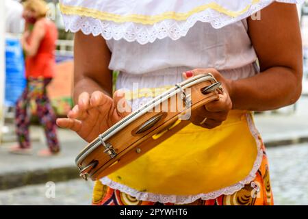 Frau in bunten ethnischen Kleidern, die während einer Samba-Vorstellung in Salvador, Bahia, Brasilien, Tamburin spielt Stockfoto