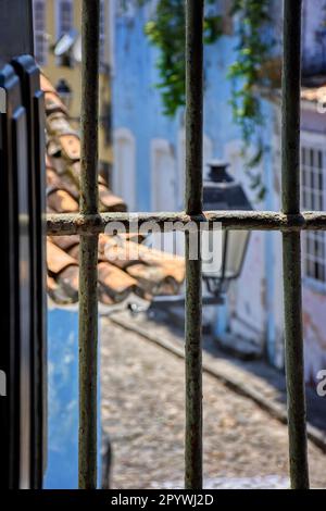 Alte Straße mit Kopfsteinpflaster im Pelourinho-Viertel Salvador, Bahia durch das Fenster und die Bars einer historischen Kirche, Brasilien Stockfoto