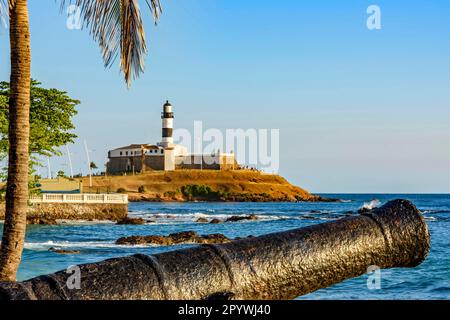 Alte Kanone und der Leuchtturm von Barra (Farol da Barra), eines der wichtigsten historischen Gebäude und Touristenattraktionen in der Stadt Salvador in Bahia Stockfoto