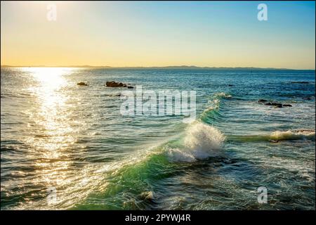 Sonnenuntergang über dem Wasser des Meeres in der Stadt Salvador in Bahia mit kleinen Wellen entlang der Felsen, Brasilien Stockfoto