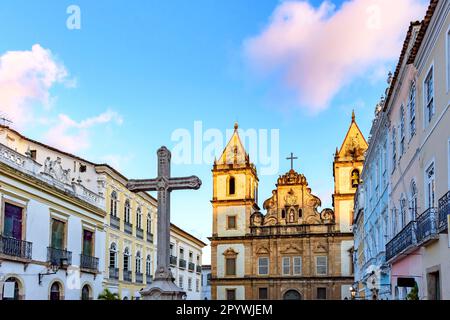 Alte Häuser und Kirchen im kolonialen und barocken Stil mit einem Kruzifix auf dem zentralen Platz des historischen Pelourinhoviertels in Salvador, Bahia Stockfoto
