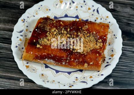 Apfelkuchen gefüllt mit cremigem Apfel, Zimt und süßem Honigsirup und garniert mit Pistazien und Nüssen, köstlicher süßer gebackener Apfelkuchen Stockfoto