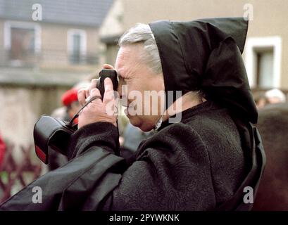 Brandenburg-Sachsen / Minderheiten / Slawen / 1996 Osterfahrt in der Nähe von Wittichenau. Sorbische Männer reiten in das nächste Dorf, um die gute Nachricht der Auferstehung Christi zu verkünden. Am Ende der Fahrt ist der Friedhof in Ralbitz dreimal umkreist. Pfarrer reiten mit. Eine sorbische Frau fotografiert die Prozession in Radibor // Wends / Lusatia / Sorbs / Ostern / Religion / Christentum / die östliche Eroberung in Ostdeutschland wurde bereits von Karl dem Großen begonnen, hat aber viele Rückschläge erlitten. 1168 wurde das große slawische Heiligtum auf Rügen von den Dänen und Albrecht dem Bären zerstört Stockfoto