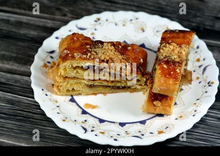 Apfelkuchen gefüllt mit cremigem Apfel, Zimt und süßem Honigsirup und garniert mit Pistazien und Nüssen, köstlicher süßer gebackener Apfelkuchen Stockfoto