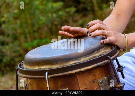 Eine Perkussionistin, die während der brasilianischen Volksmusik in Rio de Janeiro, Rio de Janeiro, Brasilien, eine Trommel namens atabaque spielte Stockfoto