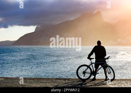 Radfahrer vor dem Meer am späten Nachmittag am Strand Arpoador in Ipanema, Rio de Janeiro, Praia do Arpoador, Ipanema, Rio de Janeiro, Rio de Stockfoto